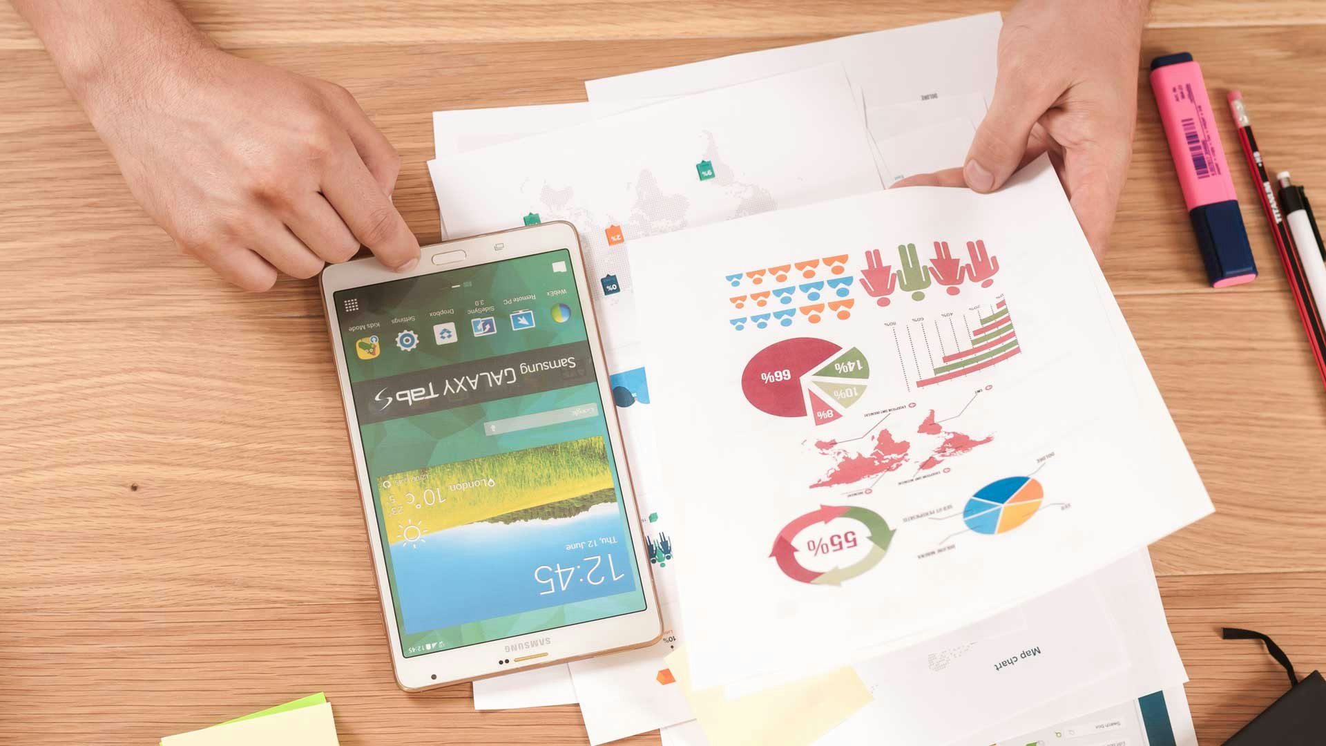 Hands Holding Paper Over Desk With Charts